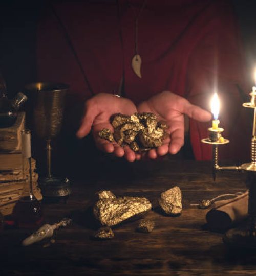 Alchemist is working at his magic table and producing a gold from a stones.